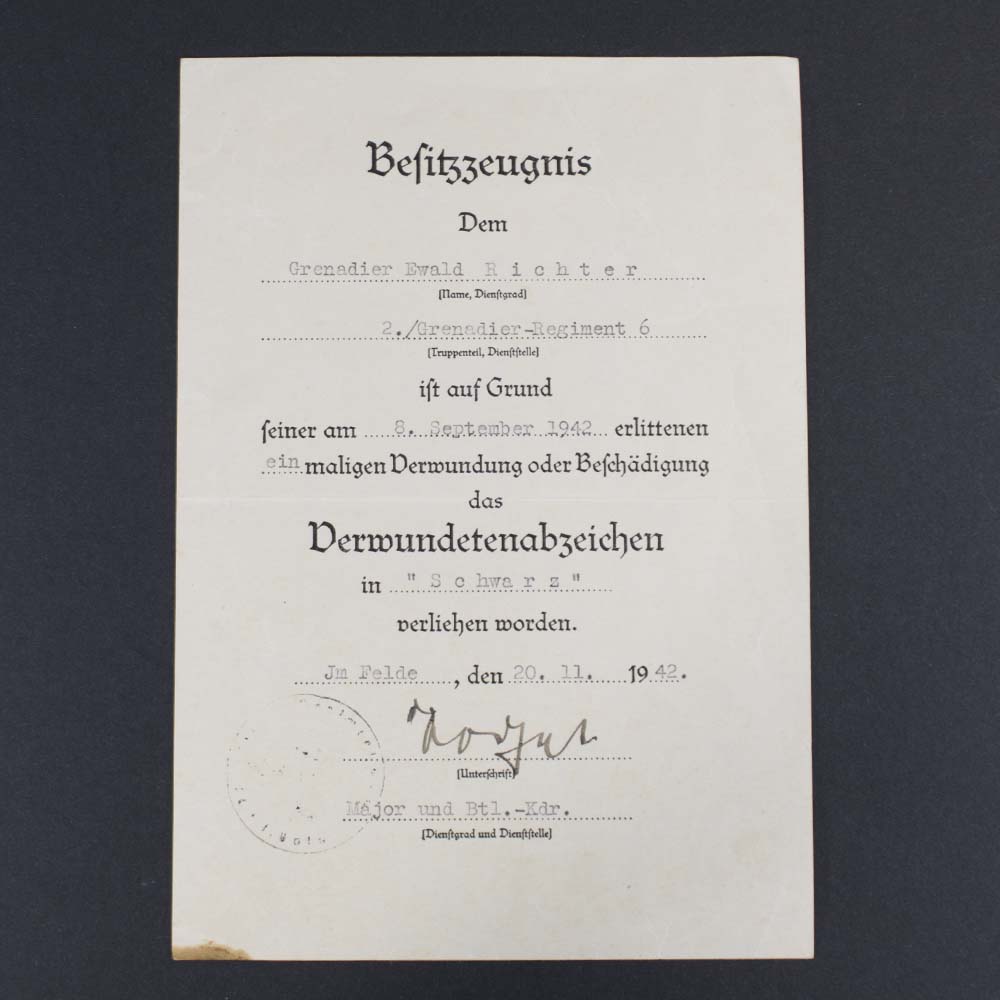 Front side of the award document for the Black Wound Badge, featuring printed German text, official stamps, and a handwritten signature, recognizing a soldier’s injury sustained in combat.