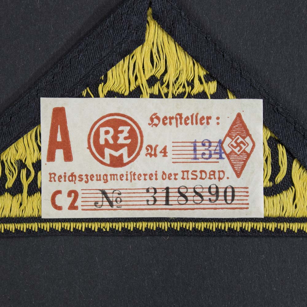 Reverse side of the Hitler Youth District Triangle, displaying the original RZM label still attached, indicating authenticity and mint condition.