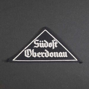 Front view of the League of German Girls District Triangle 'Südost Oberdonau', showing the black cloth triangle with white embroidered text, representing the regional designation worn on uniforms.