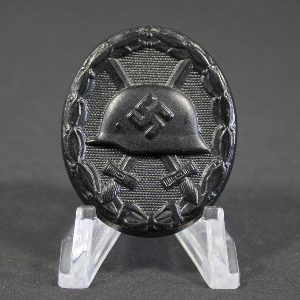 Full front view of a black German Wound Badge (Verwundetenabzeichen) in excellent condition, oval shape with embossed helmet and crossed swords.