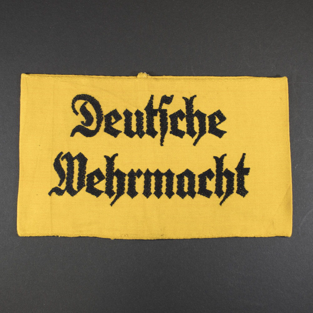 Full front view of the original WWII German Deutsche Wehrmacht armband, showing bold black text on a yelow fabric background.