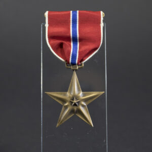 Full front view of the Bronze Star Medal, showing the five-pointed bronze star with central relief and attached ribbon in red, white, and blue.