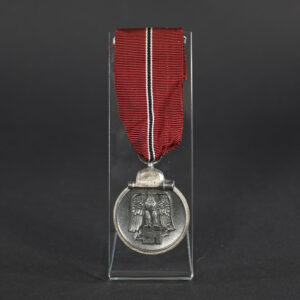 Front of a German Eastern Front Medal showing a raised design with a German eagle clutching a swastika above a crossed sword and laurel wreath, with a helmet and grenade motif at the bottom.