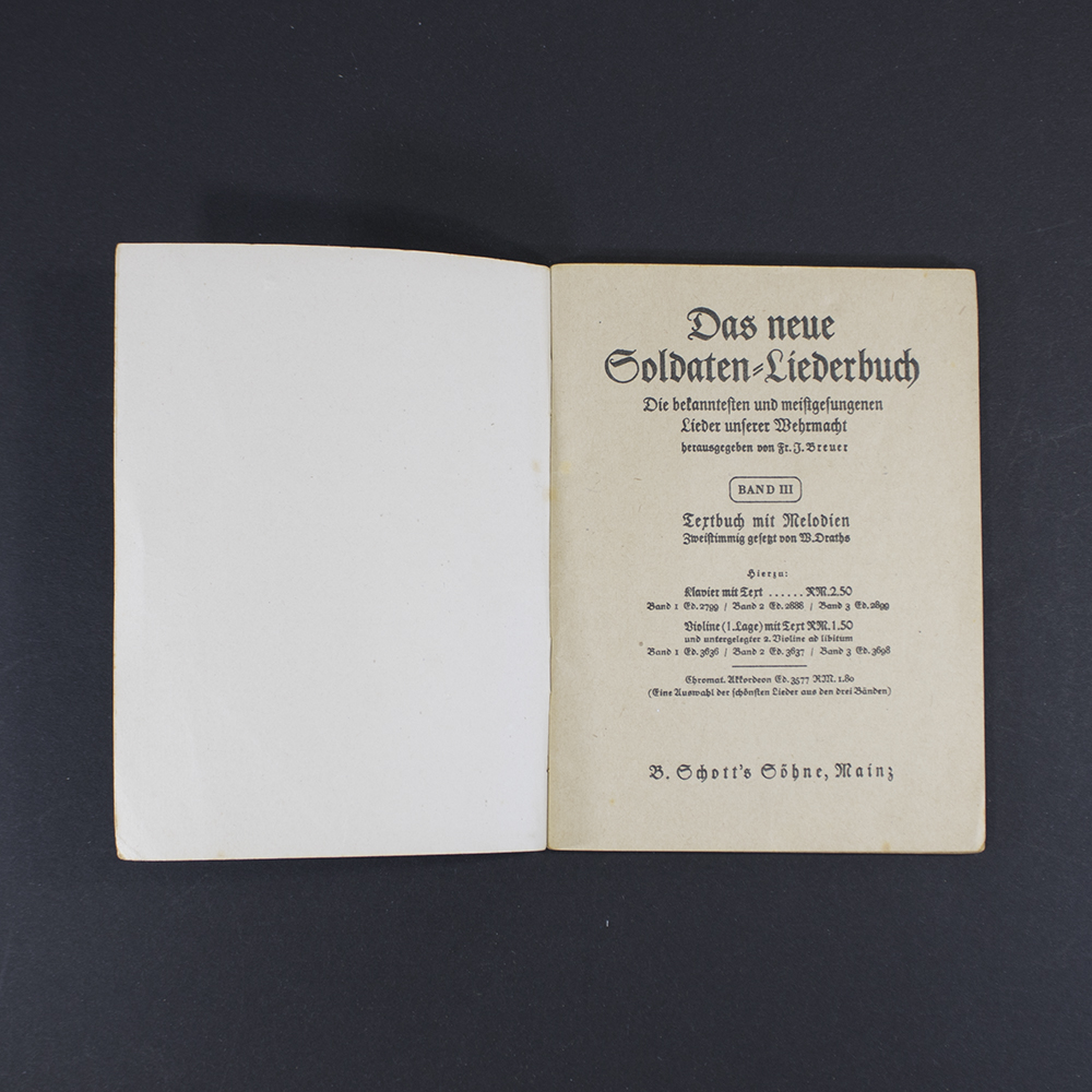 Open pages of the songbook ‘Das neue Soldaten Liederbuch’ displaying printed lyrics in Gothic typeface with musical notation above the text.