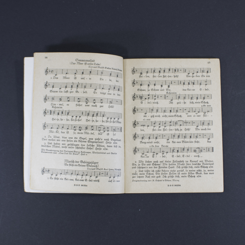 Open pages of the songbook ‘Das neue Soldaten Liederbuch’ displaying printed lyrics in Gothic typeface with musical notation above the text.