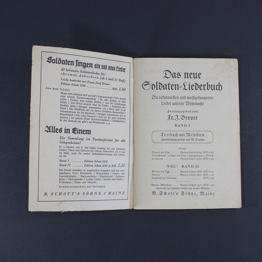 Open pages of the songbook ‘Das neue Soldaten Liederbuch’ displaying printed lyrics in Gothic typeface with musical notation above the text.