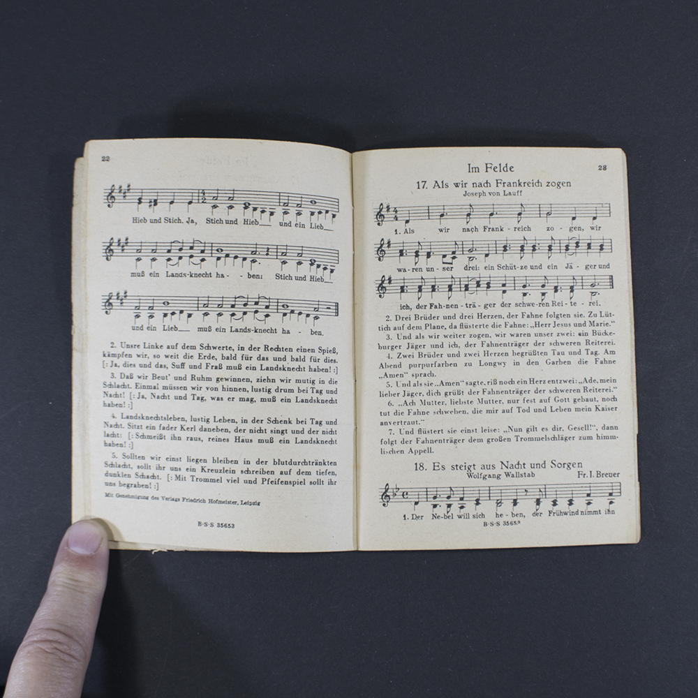 Open pages of the songbook ‘Das neue Soldaten Liederbuch’ displaying printed lyrics in Gothic typeface with musical notation above the text.