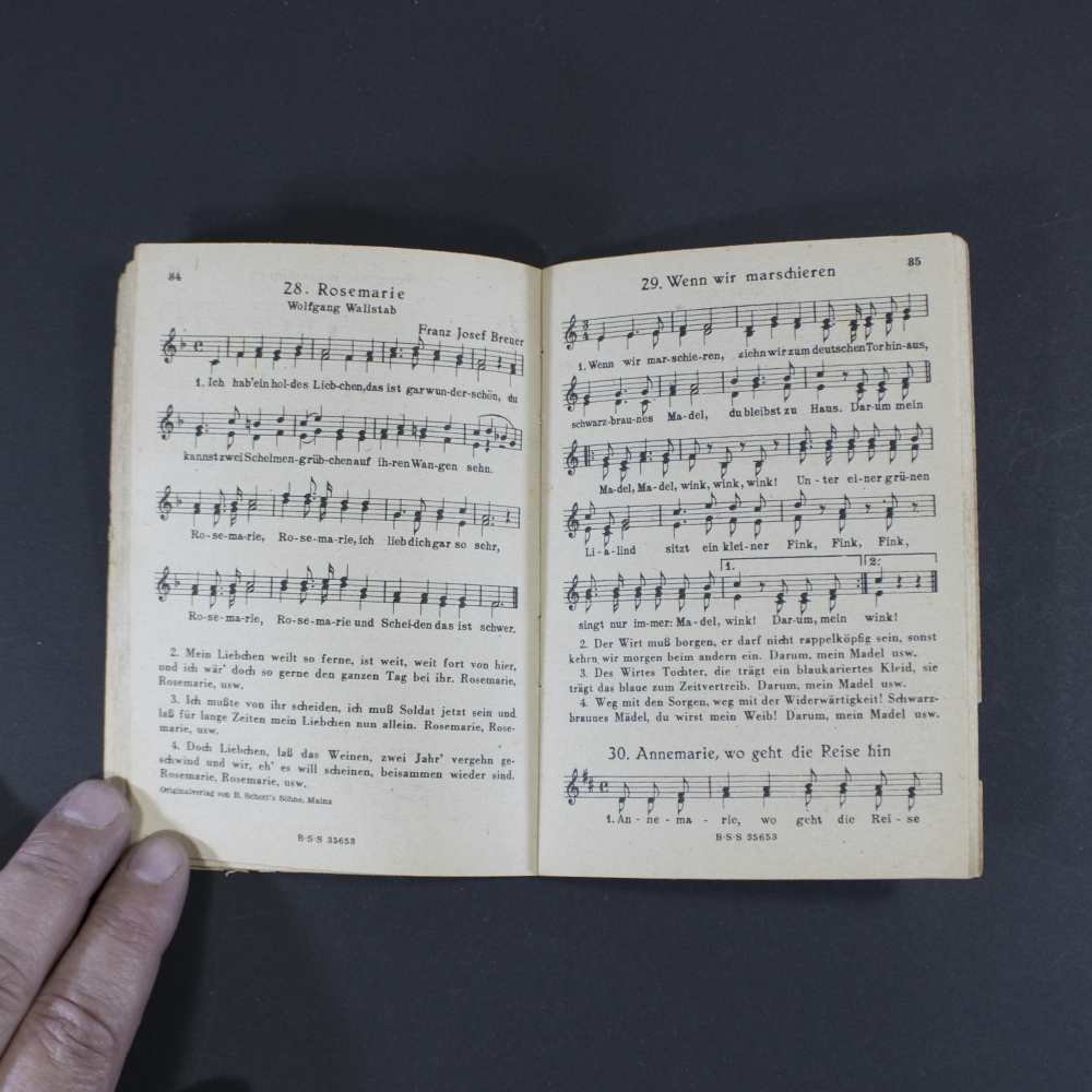 Open pages of the songbook ‘Das neue Soldaten Liederbuch’ displaying printed lyrics in Gothic typeface with musical notation above the text.