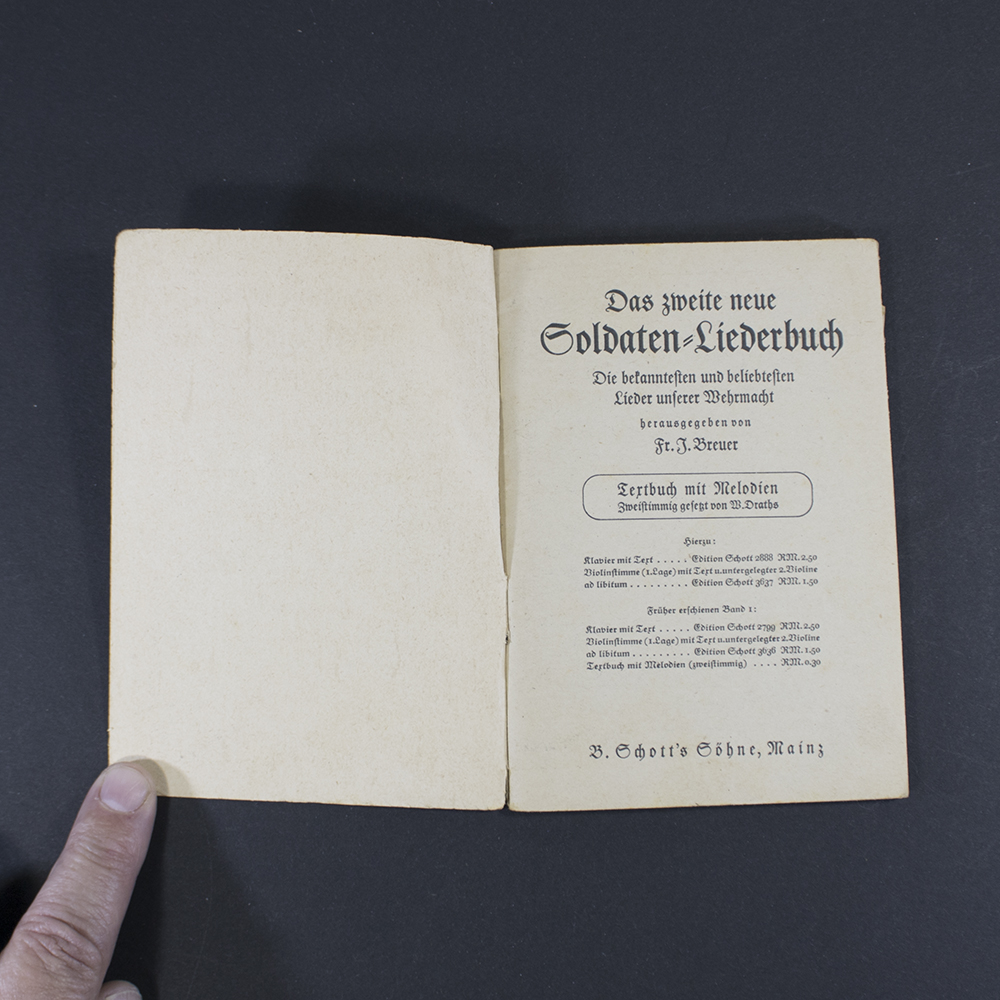 Open pages of the songbook ‘Das neue Soldaten Liederbuch’ displaying printed lyrics in Gothic typeface with musical notation above the text.