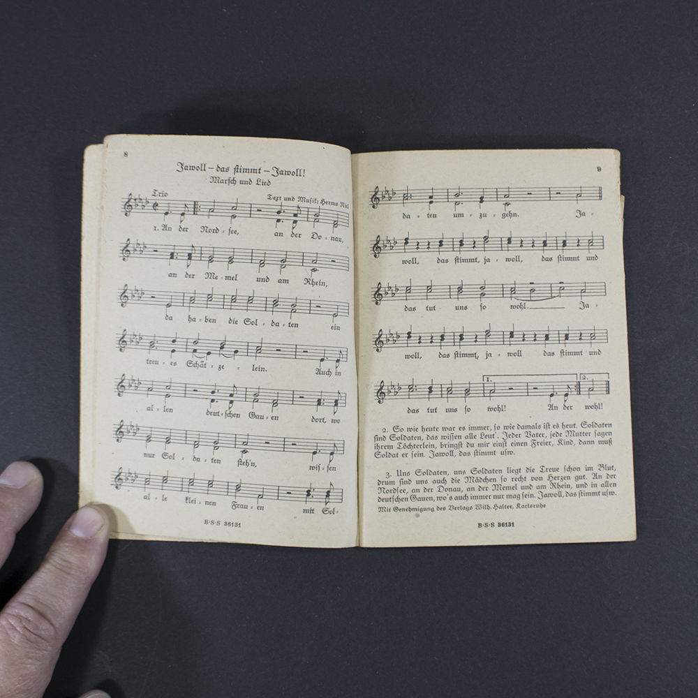 Open pages of the songbook ‘Das neue Soldaten Liederbuch’ displaying printed lyrics in Gothic typeface with musical notation above the text.