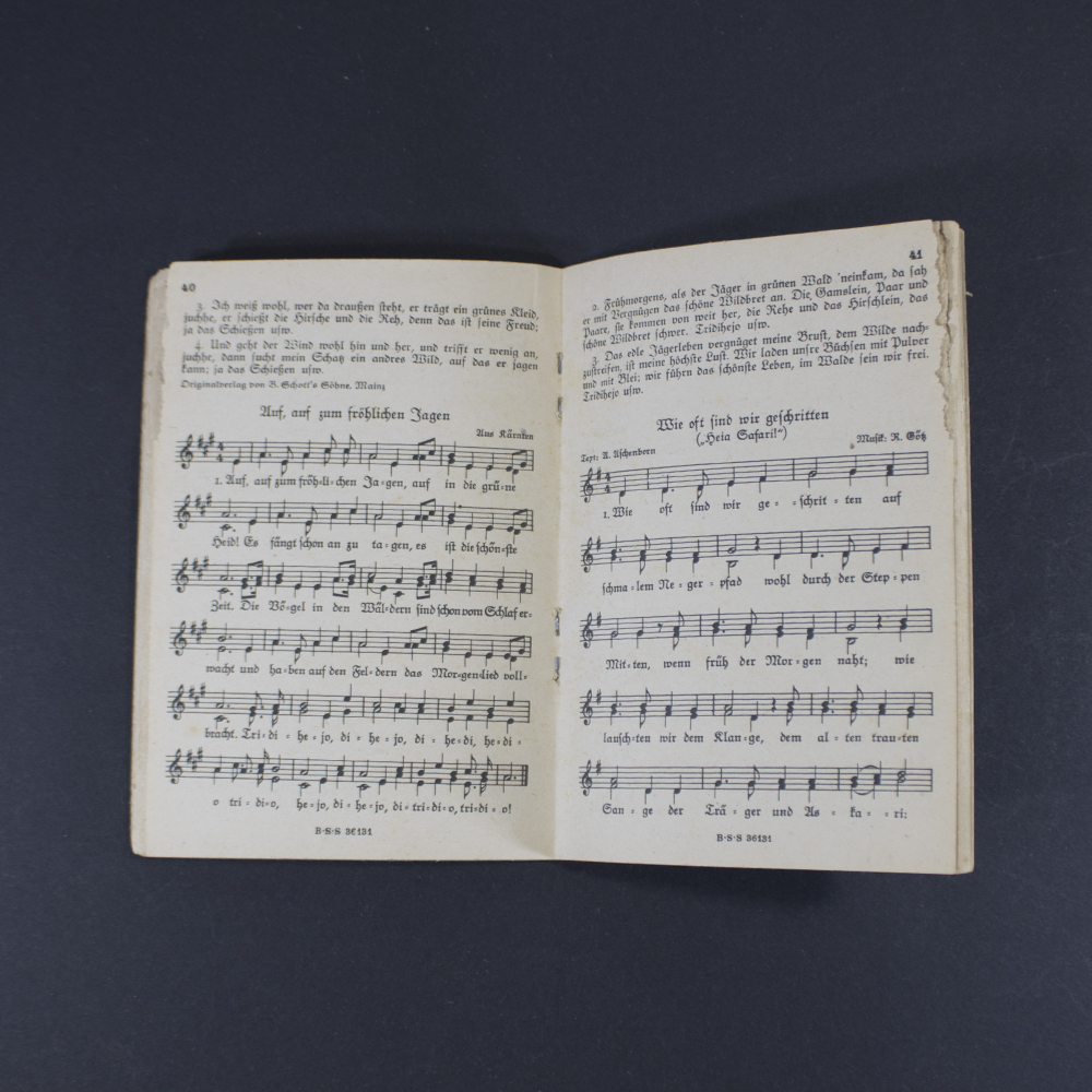 Open pages of the songbook ‘Das neue Soldaten Liederbuch’ displaying printed lyrics in Gothic typeface with musical notation above the text.