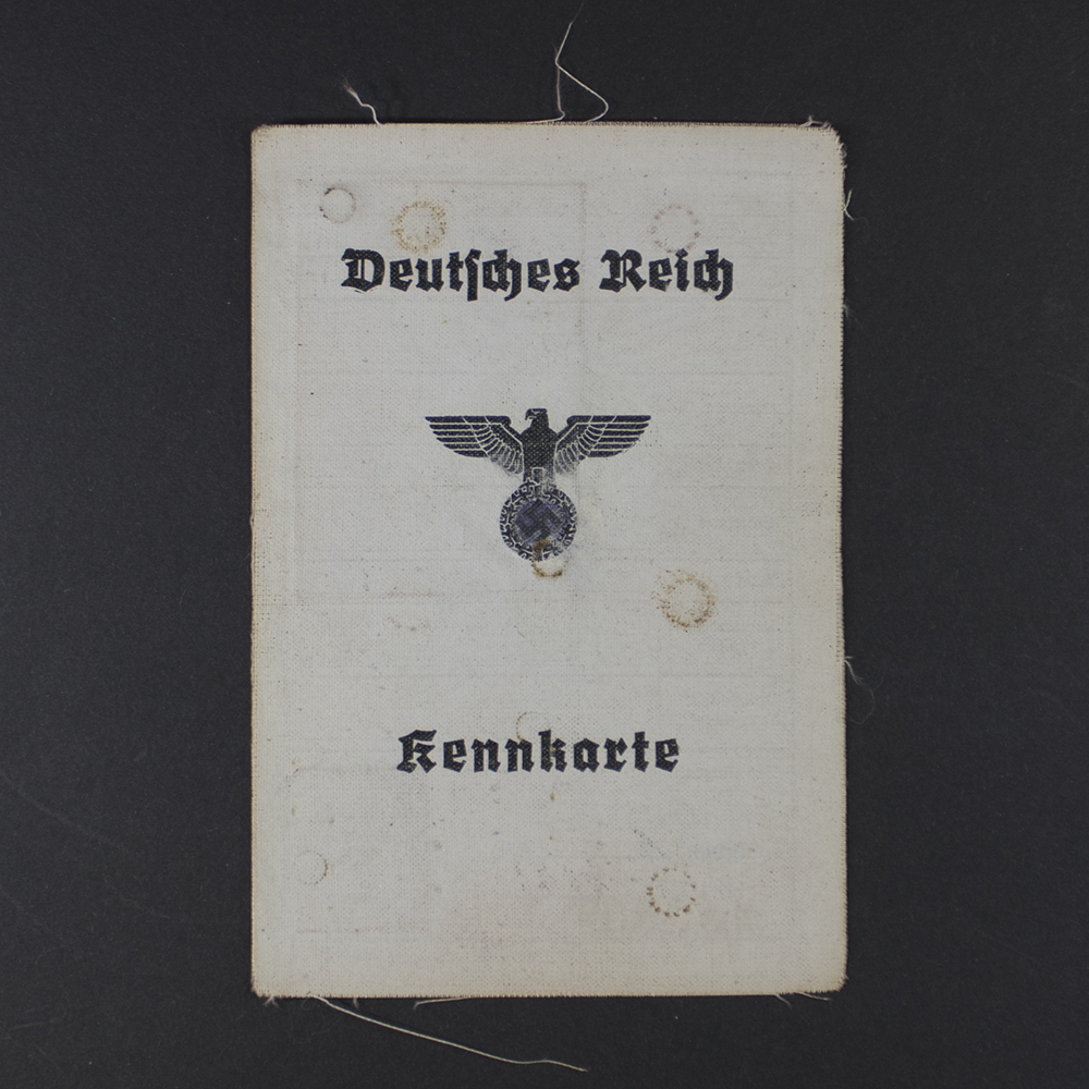 A rectangular, aged identity document with a gray-brown cover. At the top is “Deutsches Reich” in black letters, with an eagle and swastika as the official emblem.
