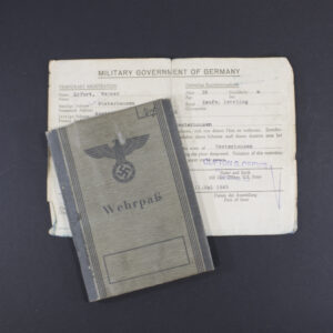 Front cover of a WWII German Wehrpass showing the title ‘Wehrpass’ in Gothic script beneath the national eagle and swastika emblem, printed on gray textured paper.