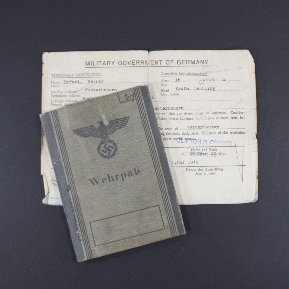Front cover of a WWII German Wehrpass showing the title ‘Wehrpass’ in Gothic script beneath the national eagle and swastika emblem, printed on gray textured paper.