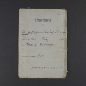 A rectangular document with a worn beige cover featuring black printed text in German. At the top is the title “Führerschein” in bold, followed by official stamps and a handwritten name. The paper shows signs of aging with creases and slight discoloration.