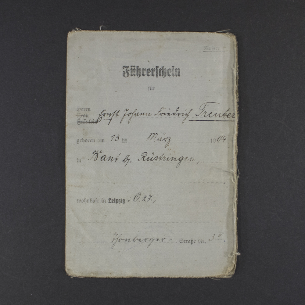 A rectangular document with a worn beige cover featuring black printed text in German. At the top is the title “Führerschein” in bold, followed by official stamps and a handwritten name. The paper shows signs of aging with creases and slight discoloration.