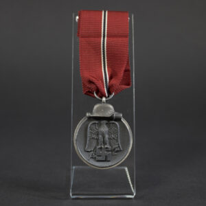 A WWII German Eastern Front Medal with a dark gray finish and a suspension ring at the top. The medal is oval-shaped and shows signs of age.