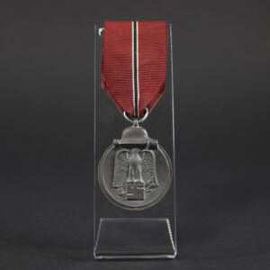 A WWII German Eastern Front Medal with a dark gray finish and a suspension ring at the top. The medal is oval-shaped and shows signs of age.