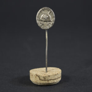 Full view of a World War II silver wound badge pin, showing its oval shape and attached pin mechanism