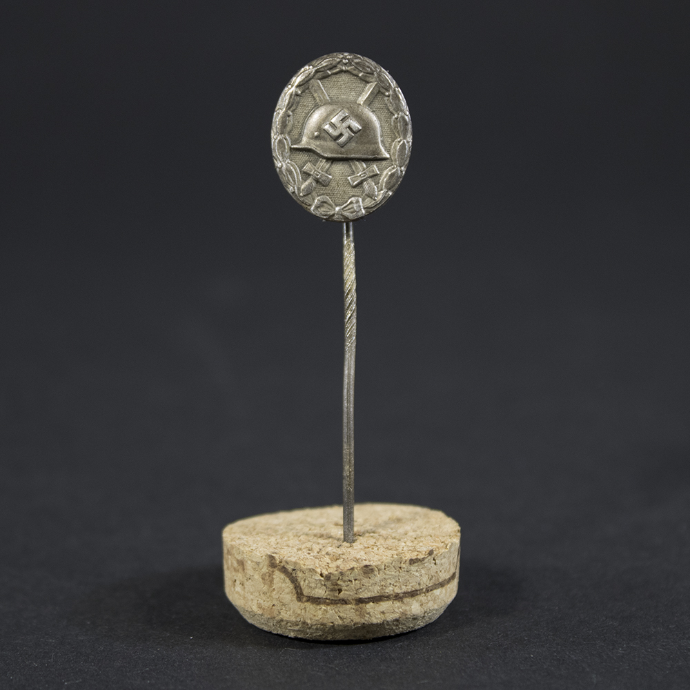 Full view of a World War II silver wound badge pin, showing its oval shape and attached pin mechanism