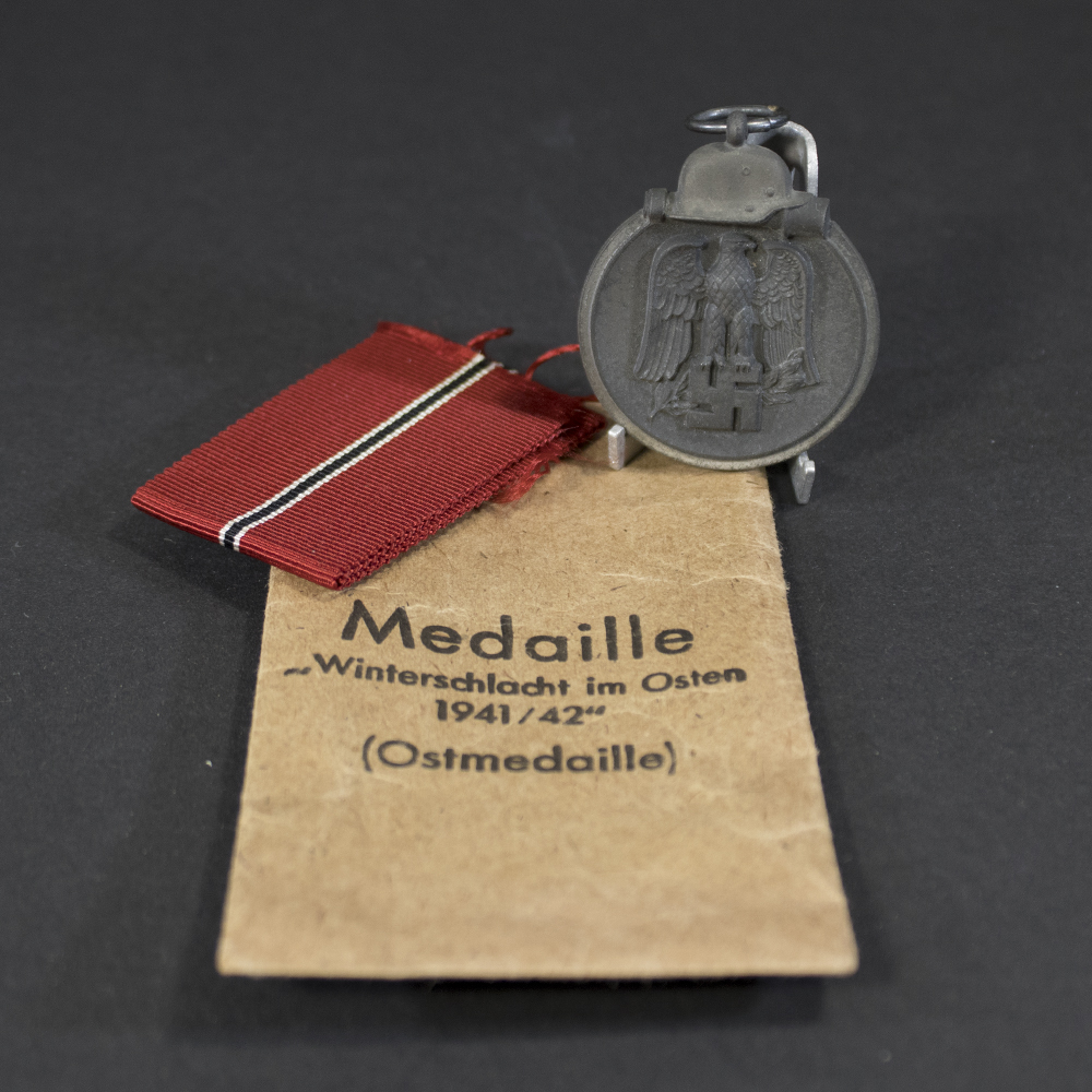 Eastern Front Medal and bag of issue displayed on a neutral background, showing the full medal with ribbon attached.