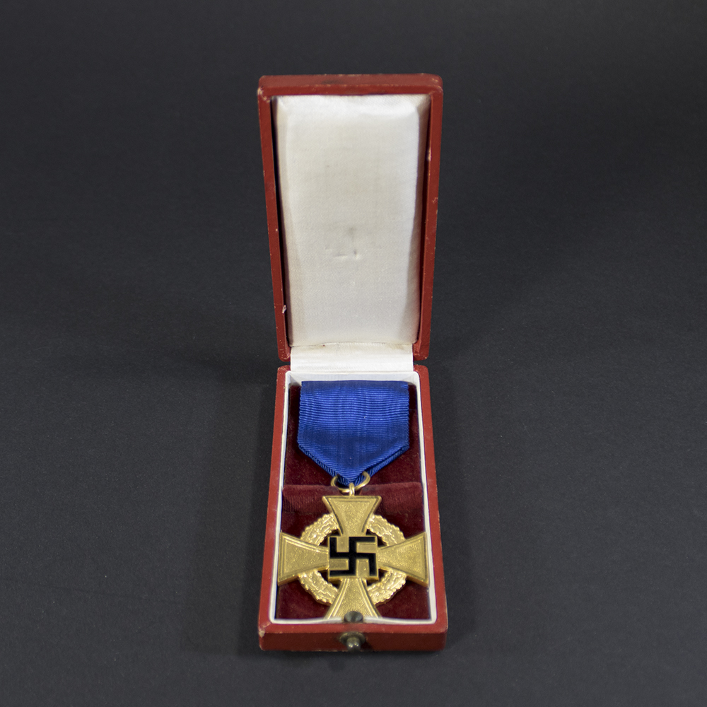 The Faithful Service Medal displayed inside its original dark-colored case. The medal is silver-toned with a blue ribbon, resting on a velvet lining.