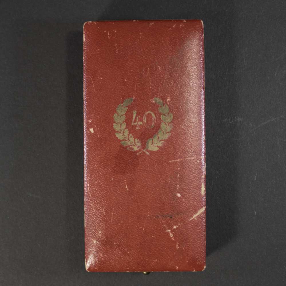 The case is rectangular, covered in dark leatherette material with a textured finish. The lid has a faint embossed design.