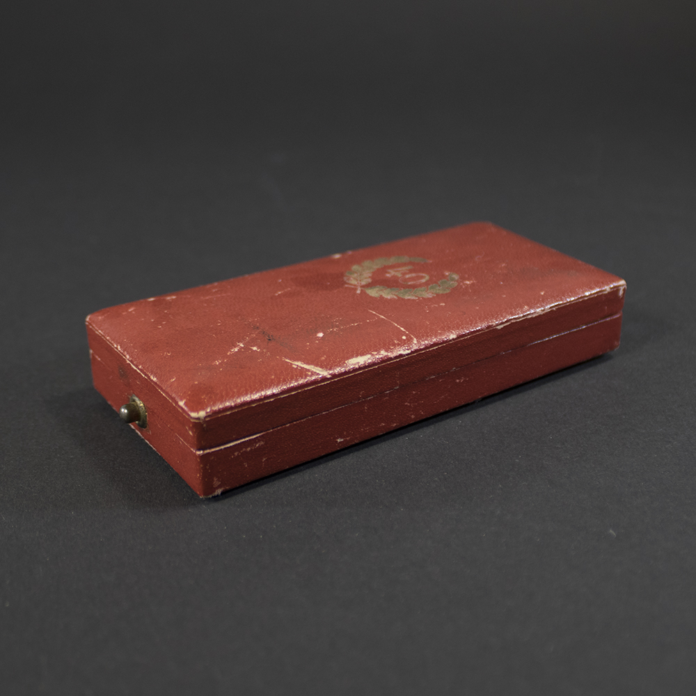 Images showing the case from different angles, highlighting its hinged structure and worn edges. The interior lining and ribbon placement are partially visible.