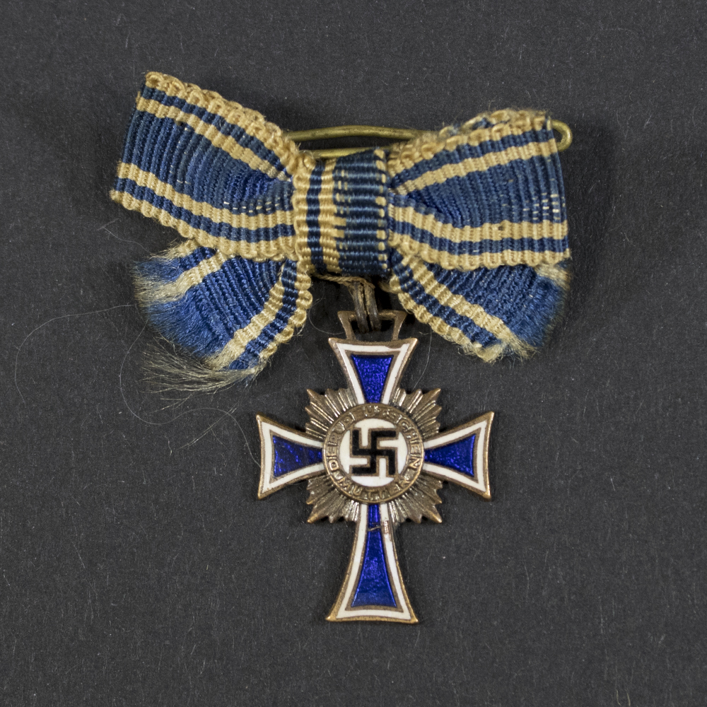 German Mother’s Cross miniaturein bronze, with white enamel arms bordered in blue, central swastika, and inscription ‘Der Deutschen Mutter.