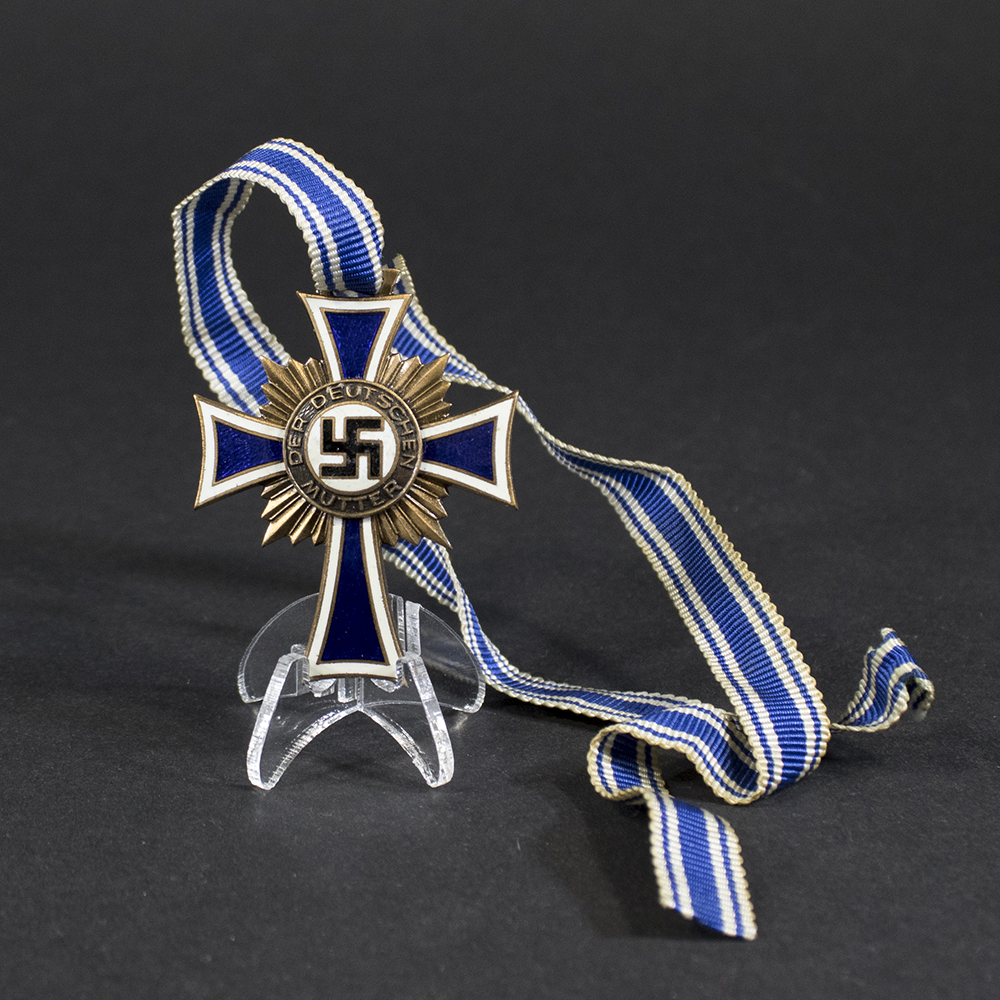 German Mother’s Cross in bronze, with white enamel arms bordered in blue, central swastika, and inscription ‘Der Deutschen Mutter'
