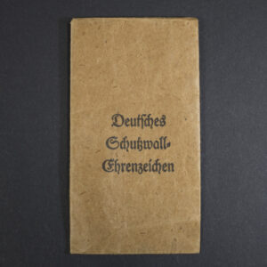 Light brown paper bag with printed text “Deutsches Schutzwall-Ehrenzeichen” in black ink. The surface shows creases and aging spots.