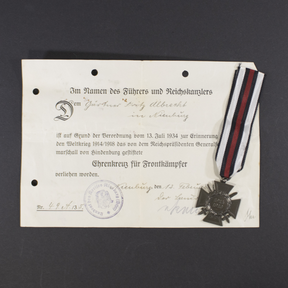 “Overview of the Frontkämpfer set, showing the medal placed alongside its award document. The medal is oval-shaped with embossed design, and the document features Gothic-style German text and official stamps.”