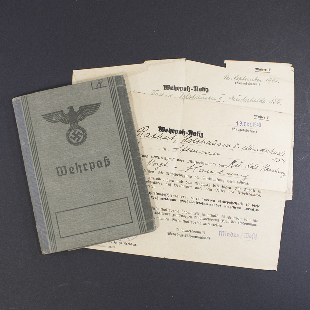 Full view of a World War II German Wehrpass displayed alongside two additional military documents.
