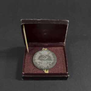 Full view of a German WWII silver wound badge displayed inside its original red presentation case with velvet lining.