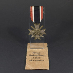 Complete World War II German War Merit Cross with Swords set displayed, including the medal and its original paper bag.