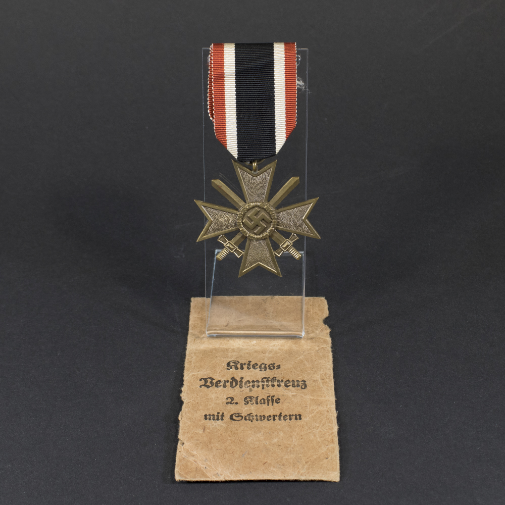 Complete World War II German War Merit Cross with Swords set displayed, including the medal and its original paper bag.