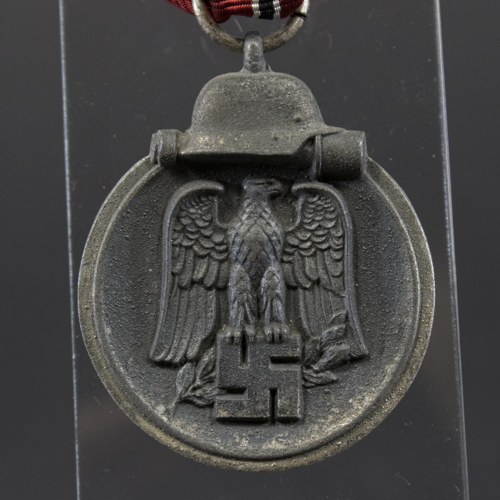 Front side of the WWII German Eastern Front Medal, featuring the eagle emblem and crossed swords with visible wear and patina.