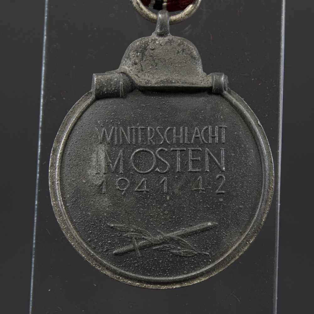 Back side of the WWII German Eastern Front Medal, showing smooth surface with slight aging marks and the suspension ring attached