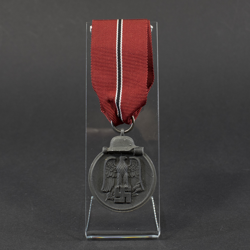 World War II German Eastern Front Medal displayed flat, showing its oval shape with a loop at the top and detailed embossed design.