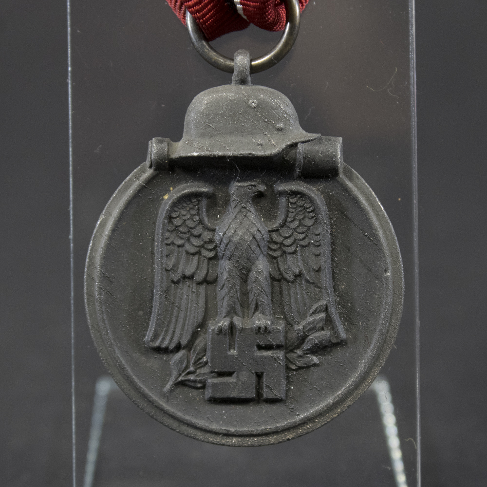 Front side of the WWII German Eastern Front Medal, featuring the eagle emblem and crossed swords with visible wear and patina.