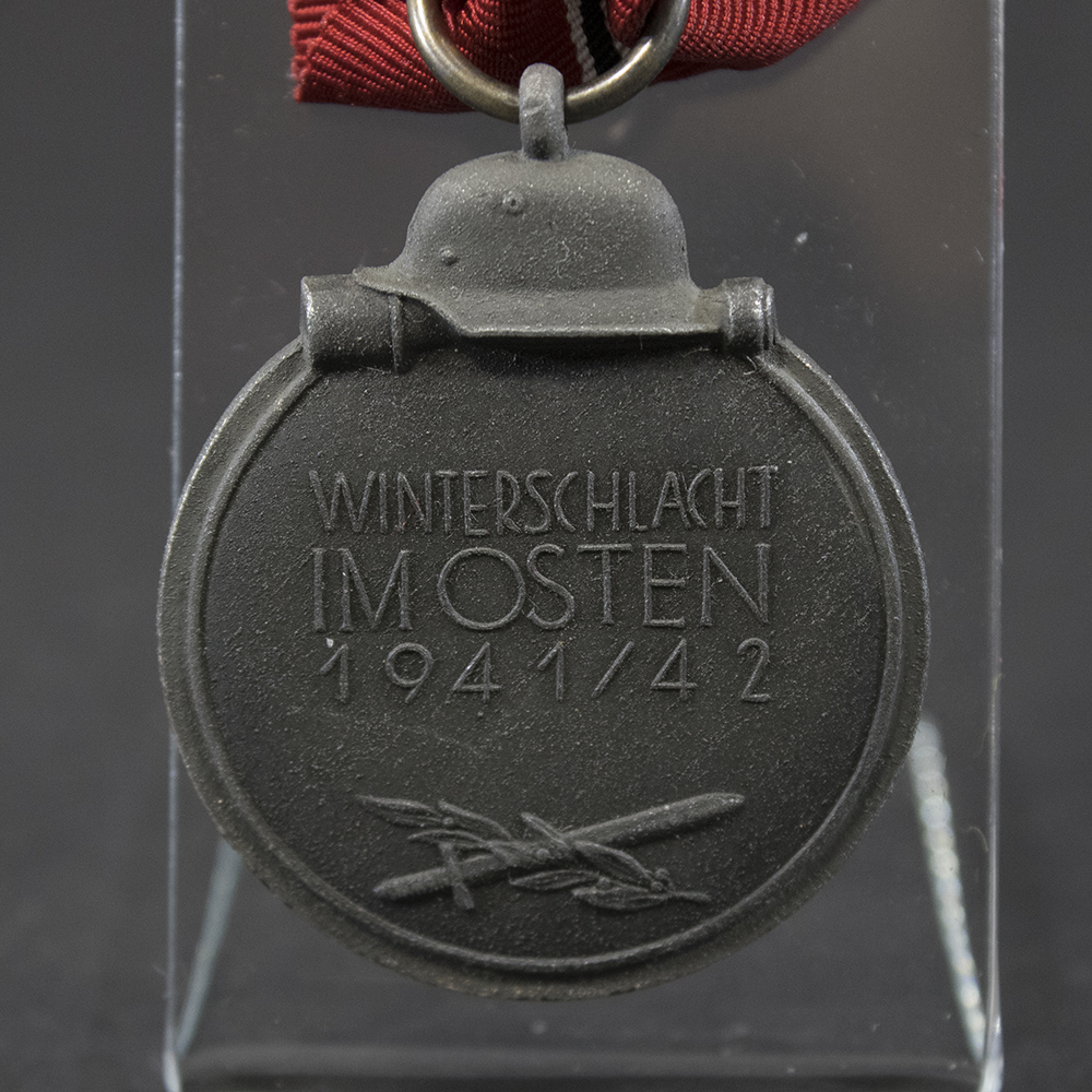Back side of the WWII German Eastern Front Medal, showing smooth surface with slight aging marks and the suspension ring attached.
