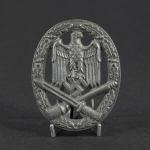 Overview of a WWII German General Assault Badge, oval-shaped metal badge featuring an eagle and crossed weapons surrounded by a wreath.