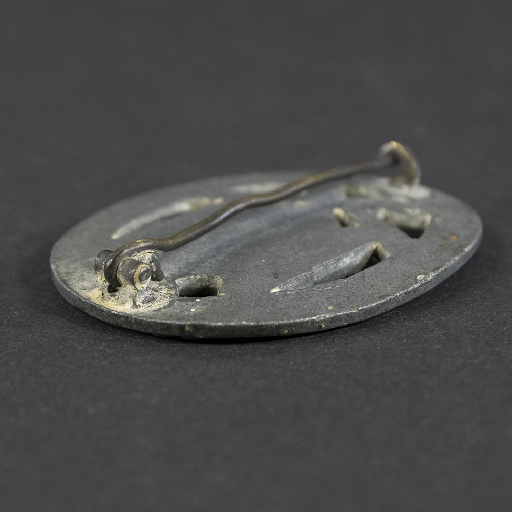 Detailed close-up of the hinge on the back of a WWII German General Assault Badge, showing construction and wear.
