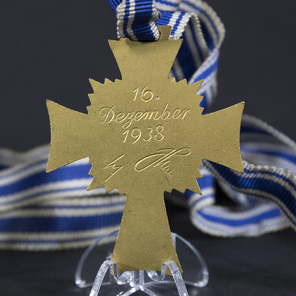 Reverse side of the gold Mother’s Cross, displaying the engraved dedication and smooth golden surface.