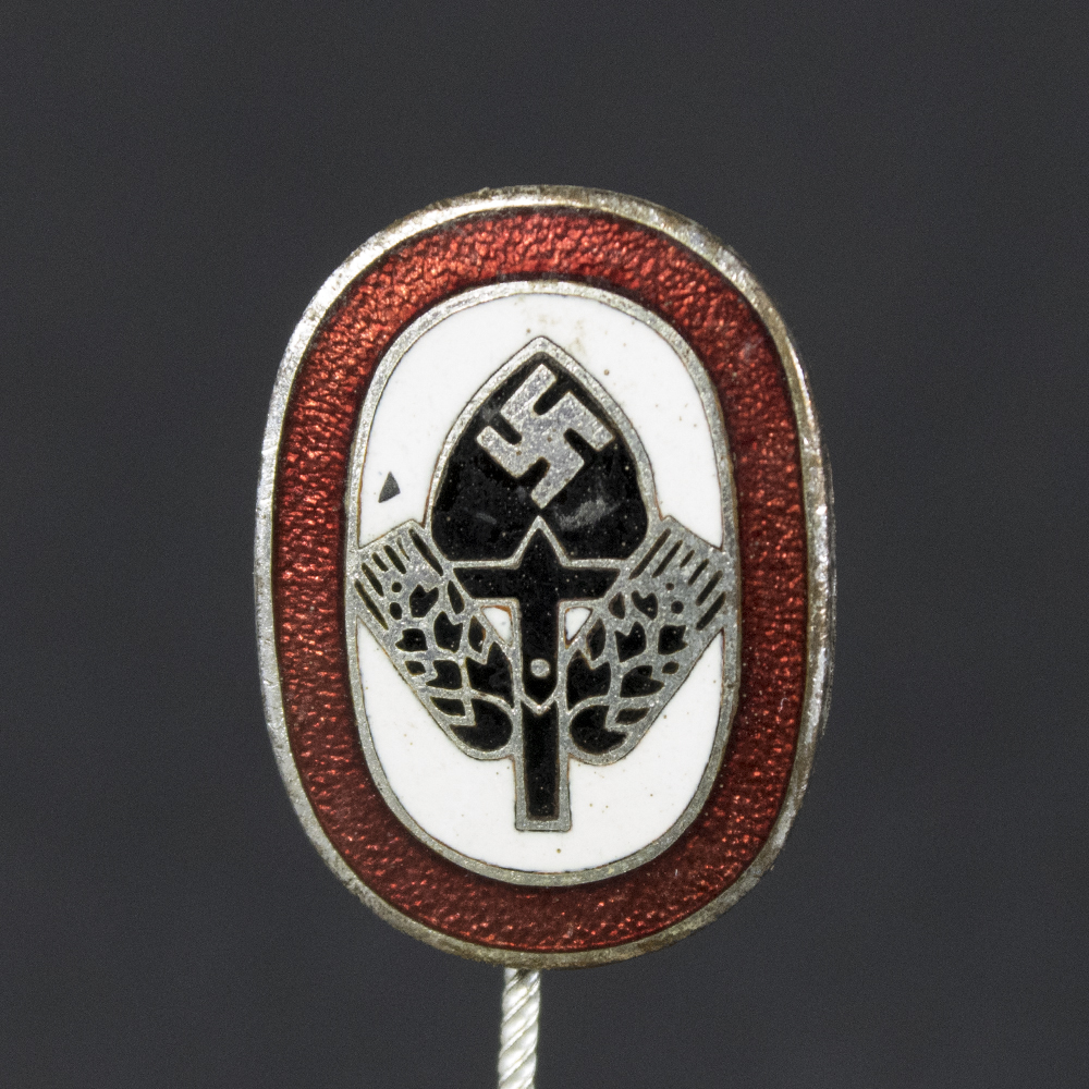 Front side of the WWII German Reichsarbeitsdienst membership stick pin, featuring the detailed design with spade symbol and crossed wheat sheaves on a silver-toned background.