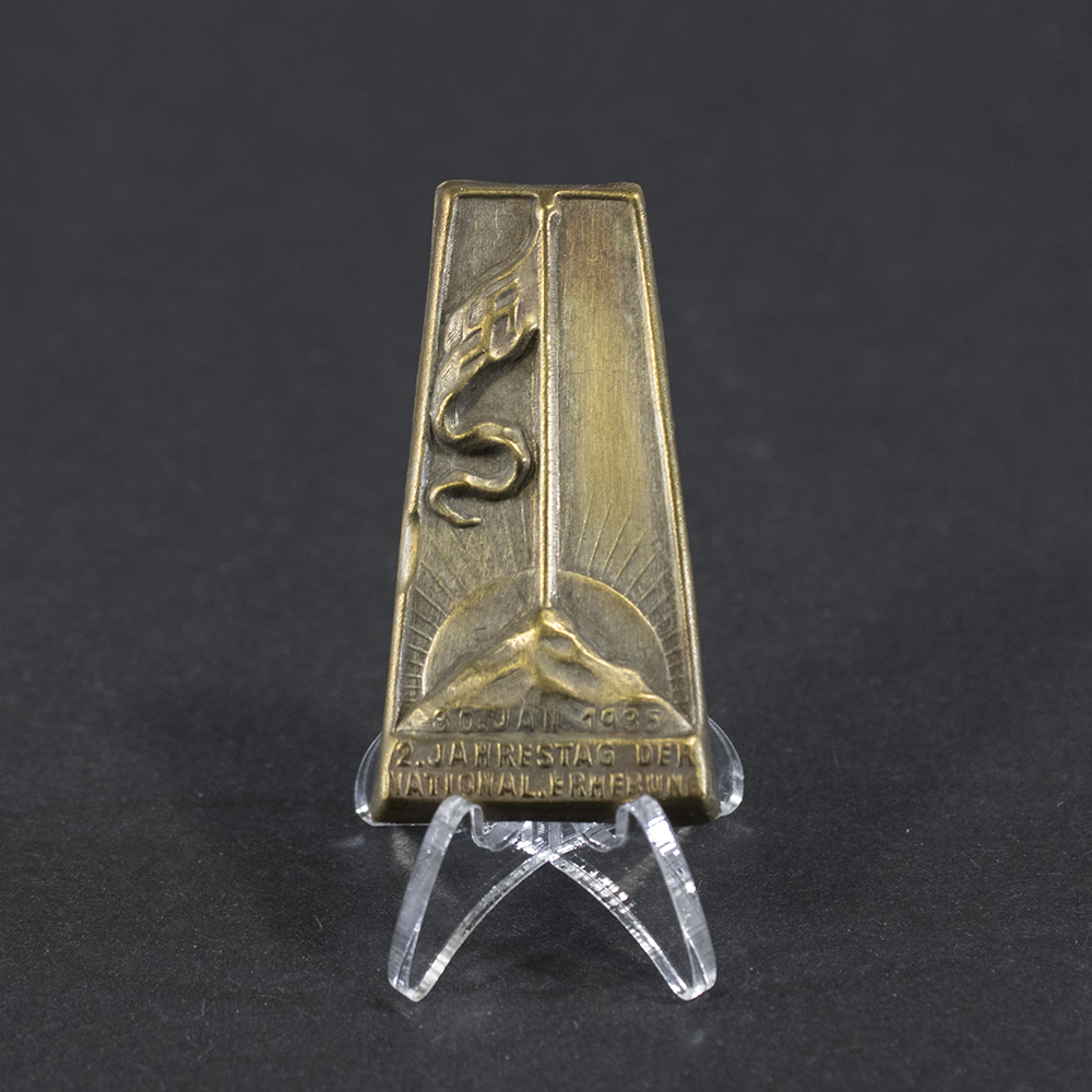 Overview of a German “Jahrestag der Nationalen Erhebung” tinnie, showing the small commemorative metal badge.