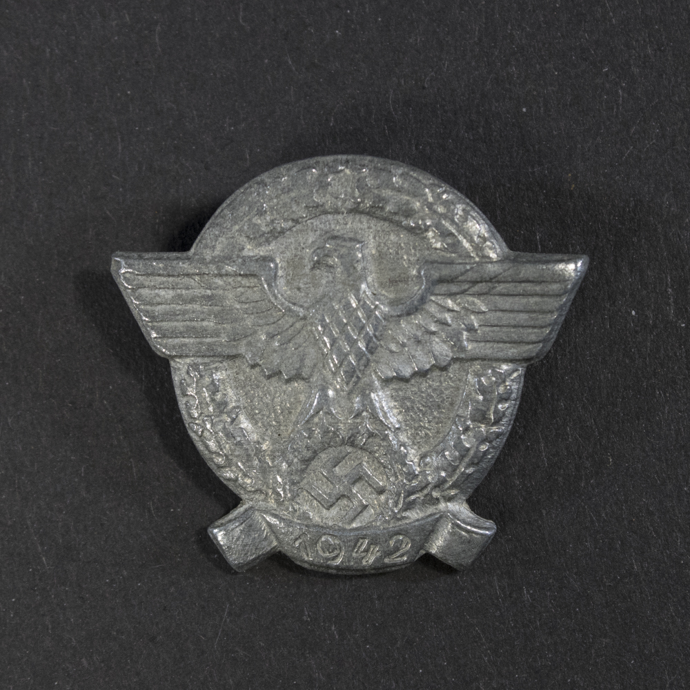 World War II German WHW ‘Tag der Deutschen Polizei 1942’ tinnie displayed flat, showing its rectangular badge with raised design and pin attachment on the back.
