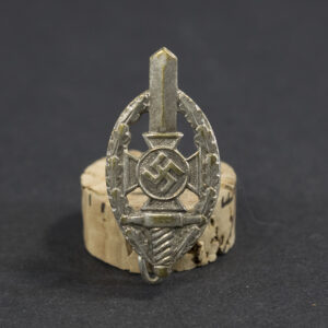 Overview of a WWII German NSKOV membership pin, showing the small metal badge with its enamel design and fastening post.