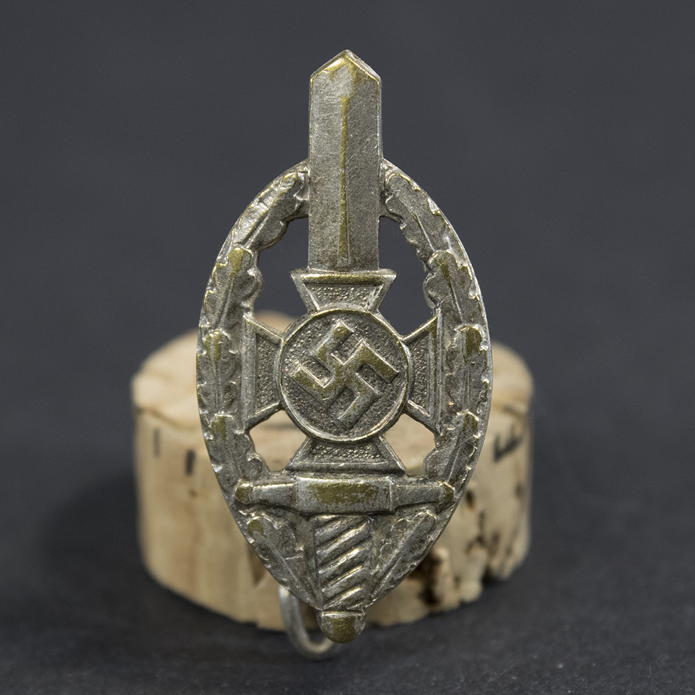 Close-up of the front of a WWII German NSKOV membership pin, showing the detailed enamel emblem and lettering.