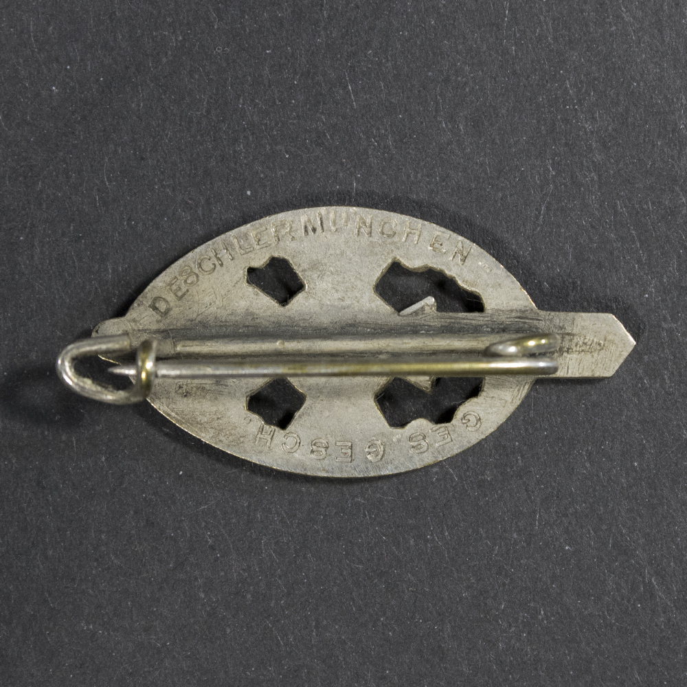 Close-up of the reverse of a WWII German NSKOV membership pin, showing the plain metal back and pin fastening mechanism.